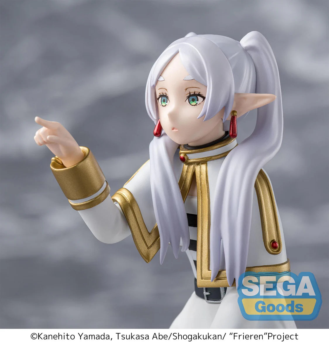 Figurine of Frieren with white hair and gold accents, pointing forward, against a gray background with Sega Goods logo.