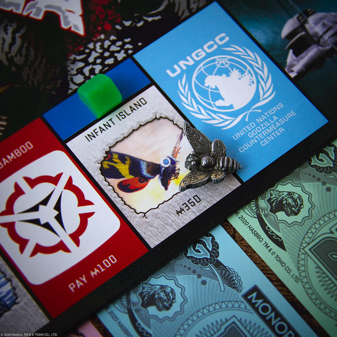 Close-up of a card featuring the UNGCC logo and a Mothra illustration, surrounded by other cards with various designs.