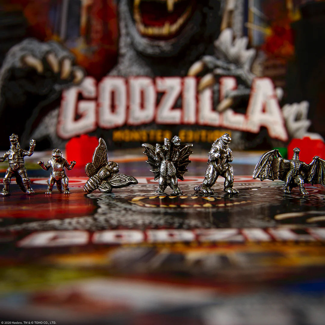 Collection of Godzilla miniatures on a display stand with a blurred Godzilla logo in the background.