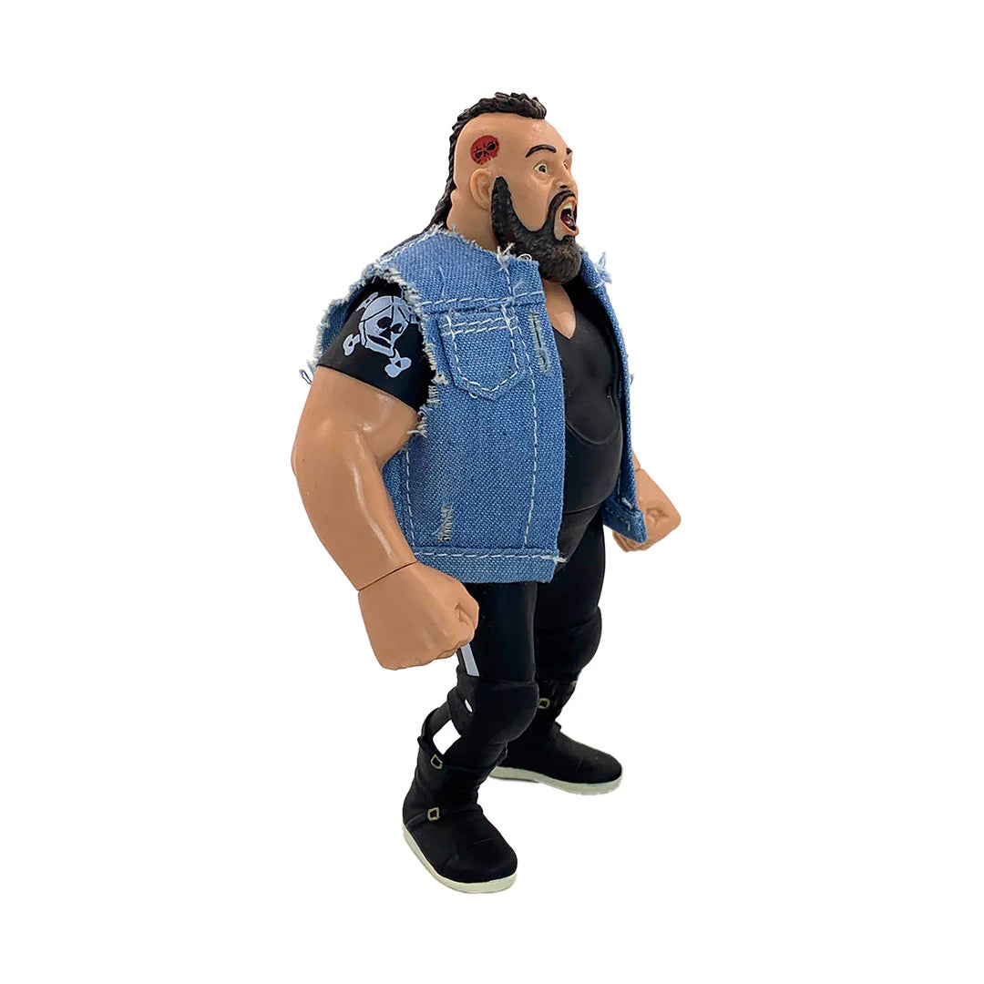 A wrestling action figure of a muscular man with a beard, wearing a distressed blue denim vest over a black shirt and black pants, standing against a plain white background. - Action Figures - Wrestling