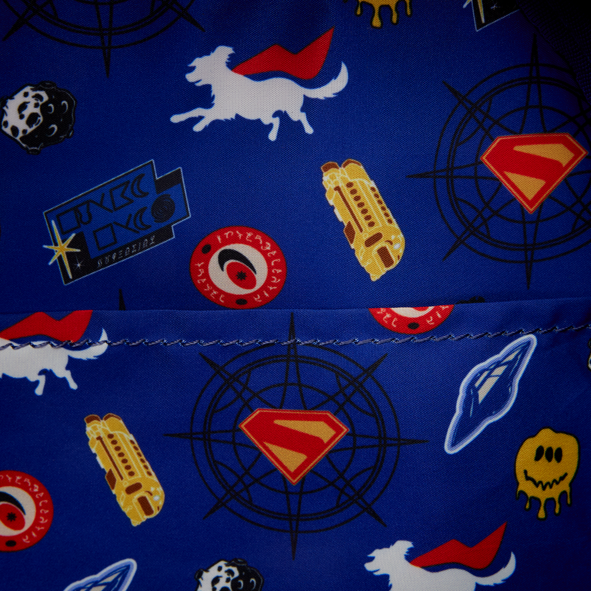 Close-up of a blue fabric with superhero-themed patterns including Superman logo, rocket, and alien. - Action Figures - DC Comics