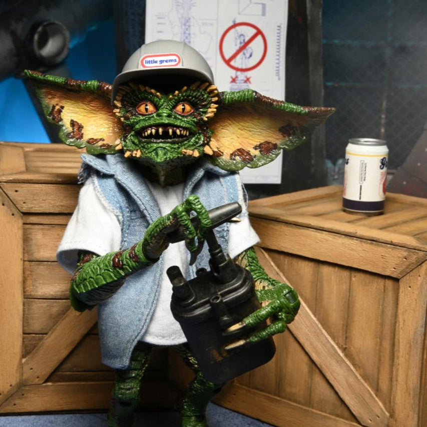 Toy figure of a green creature with a helmet, holding a drill, standing next to wooden crates and a black barrel labeled 'ACME TNT'.