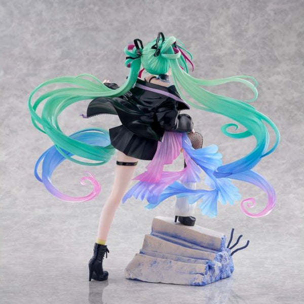 A stylized anime figurine of Hatsune Miku posed mid-dance on a gray studio background, with long flowing mint green hair, a black outfit, and translucent pastel blue, pink, and purple accents. - Statues