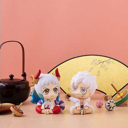 Two chibi anime figurines posed in front of a pink background with decorative props including a black teapot, a yellow folding screen, and small toy accessories. - Funko Pop